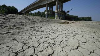 Dry cracked land is visible under a bridge in Boretto on the bed of the Po river, Italy, Wednesday, June 15, 2022