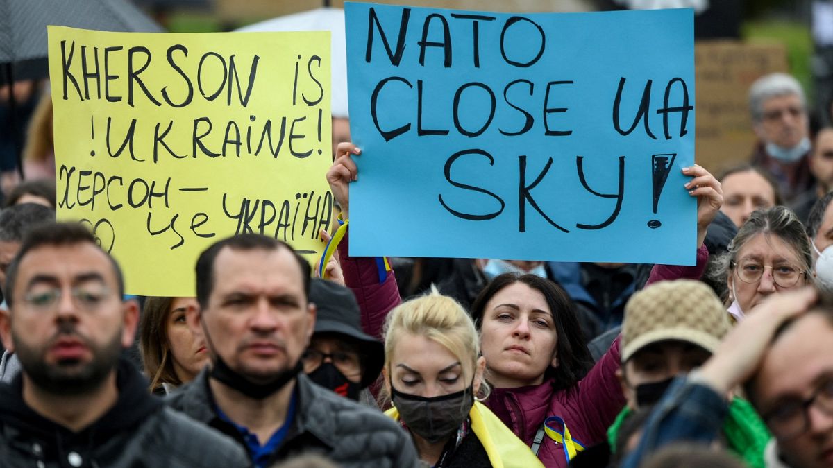 Protestors hold signs reading "Kherson is Ukraine!" and "NATO, close Ukraine's sky" during a demonstration in Kherson.