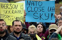 Protestors hold signs reading "Kherson is Ukraine!" and "NATO, close Ukraine's sky" during a demonstration in Kherson.