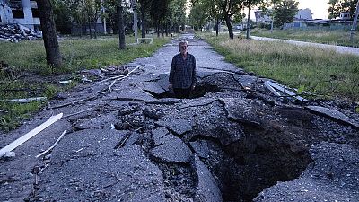 Viktor Shevchenko stands in a crater to show its depth after a Russian attack in the Saltivka district in Kharkiv, 1 July 2022