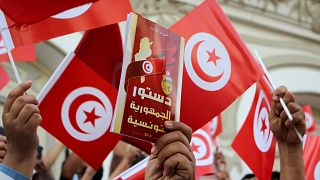 متظاهر تونسي يرفع نسخة من الدستور خلال احتجاج مناوئ للرئيس سعيّد في أيلول/سبتمبر 2021