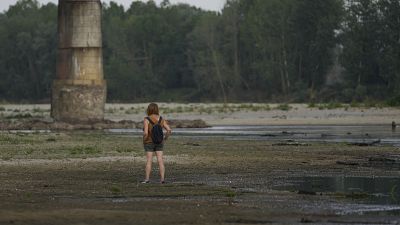 A woman stands on the Po riverbed next to Ponte della Becca (Becca bridge) in Linarolo, near Pavia, Italy, Monday, June 27, 2022