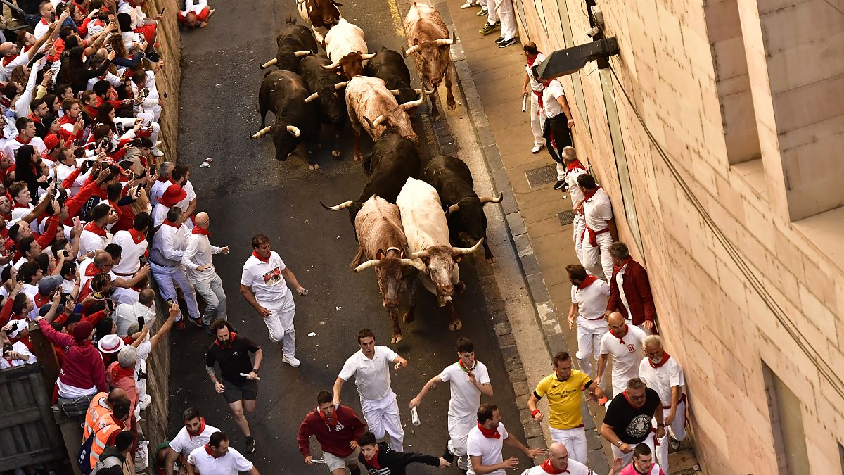 People run through the street with fighting bulls at the San Fermin Festival in Pamplona, northern Spain, Friday, July 8, 2022. 