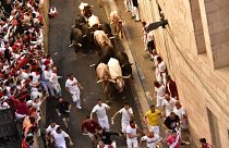 People run through the street with fighting bulls at the San Fermin Festival in Pamplona, northern Spain, Friday, July 8, 2022.