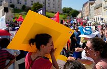 متظاهرة برتغالية تحجب عن وجهها أشعة الشمس الحارّة بيافطة تحملها خلال مظاهرة لنقابات العمال خارج البرلمان في لشبونة، 7 يوليو 2022.