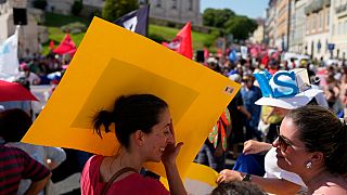 متظاهرة برتغالية تحجب عن وجهها أشعة الشمس الحارّة بيافطة تحملها خلال مظاهرة لنقابات العمال خارج البرلمان في لشبونة، 7 يوليو 2022. 