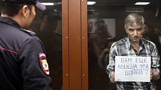 Moscow city councillor Alexei Gorinov shows a sign asking "Do you still need this war?" in court on 8 July 2022