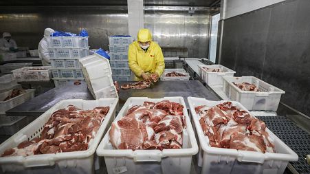 Meat being processed by a worker.