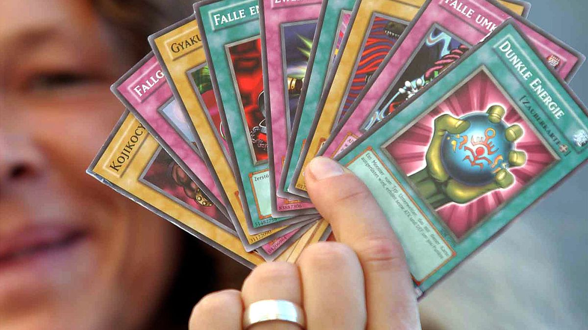 A collector holds up a full hand of Yu-Gi-Oh! cards