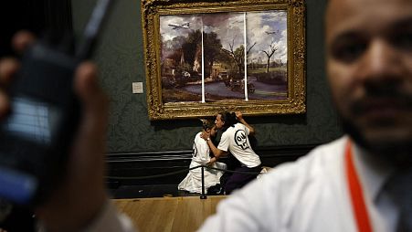 Activists from the 'Just Stop Oil' campaign group, with hands glued to the frame of the painting 'The Hay Wain' by English artist John Constable.