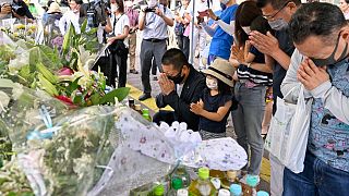 People pray at a makeshift memorial near the scene where the former Prime Minister Shinzo Abe was shot in Nara, western Japan, July 9, 2022.