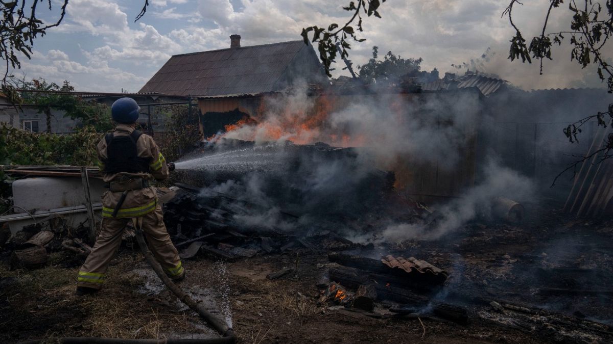 A firefighter hoses down a house on fire after cluster rockets hit a residential area, in Konstantinovka, eastern Ukraine, Saturday, July 9, 2022.