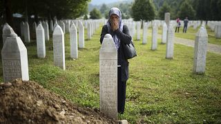 Женщина молится у могилы убитого родственника в мемориальном комплексе в Потокари неподалеку от Сребреницы. 8 июля 2022