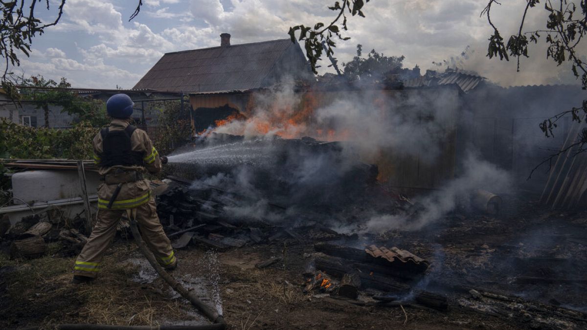 Пожарный поливает из шланга дом, в который попала ракета, в Константиновке. 9 июля 2022