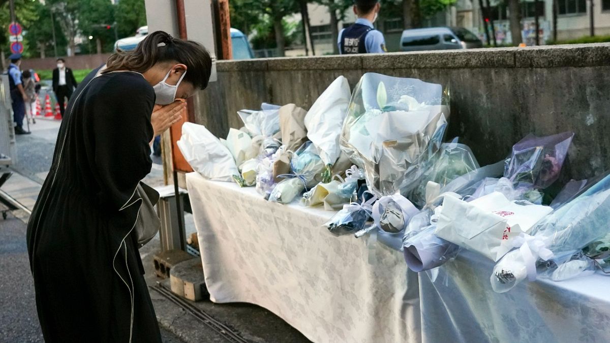A mourner offers a flower for former Japanese Prime Minister Shinzo, at the entrance of the Liberal Democratic Party (LDP) HQ building in Tokyo, Japan,  Sunday July 10, 2022. 