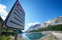 A signpost reading "avalanche danger" is seen in front of the Marmolada mountain and the Punta Rocca glacier near Canazei, in the Italian Alps in northern Italy, July 6, 2022.