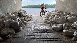A Sunday morning cyclist emerges from a sandbagged tunnel next to the Dnipro River in Kyiv, July 10, 2022. Reminders of war are visible as Russian forces attack to the east.
