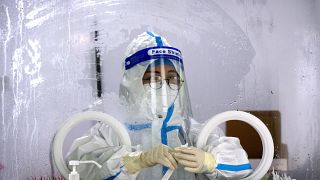 عامل يرتدي بدلة واقية وينتظر إجراء اختبار COVID-19 في موقع اختبار فيروس كورونا في بكين