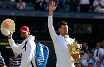 Serbia's Novak Djokovic (R) holds the winner's trophy as he celebrates after beating Australia's Nick Kyrgios (L) to win the men's singles final at Wimbledon, July 10, 2022.