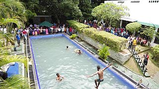 Protesters swim as onlookers wait at a swimming pool in president's official residence a day after it was stormed in Colombo