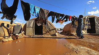 Eine Frau hängt in einem Flüchtlingslager in der Provinz Idlib, Syrien, Wäsche auf.