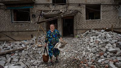 Une femme récupère des affaires personnelles, après qu'une roquette ait frappé un immeuble d'habitation, à Chasiv Yar, le 10 juillet 2022