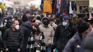 People, some wearing surgical masks, others FFP2 masks, to cope with the surge of COVID-19 cases stroll past stalls at the Porta Portese open air market, in Rome