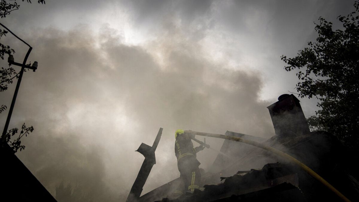 Un secouriste éteint l'incendie d'une maison détruite après une attaque russe dans un quartier du centre-ville de Kharkiv, le 11 juillet 2022.