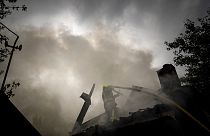 Un secouriste éteint l'incendie d'une maison détruite après une attaque russe dans un quartier du centre-ville de Kharkiv, le 11 juillet 2022.