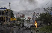 Украинские спасатели работают на месте ракетного удара по жилому квартала в Харькове
