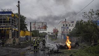 Украинские спасатели работают на месте ракетного удара по жилому квартала в Харькове