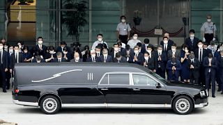 Japanese Prime Minister Fumio Kishida and officials offer prayer as the hearse carrying the body of former PM Shinzo Abe makes a stop at the PM's office in Tokyo, 12 July 2022