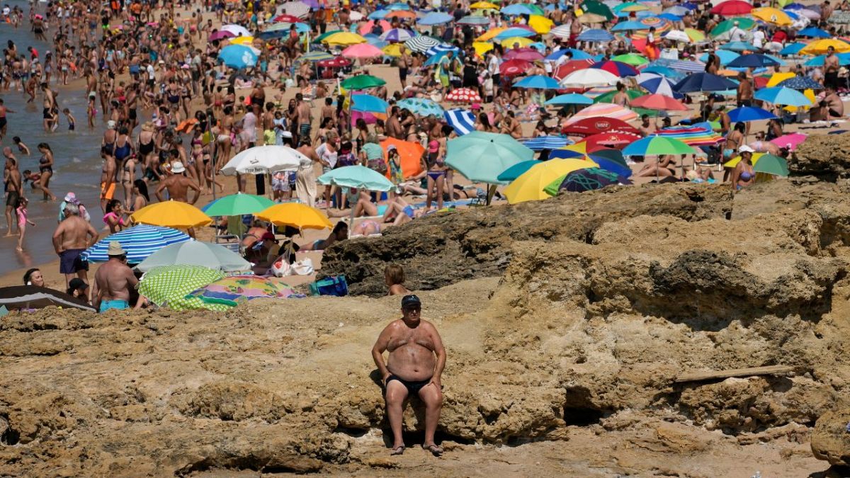 A man sits in the sun at Carcavelos beach, outside Lisbon, Friday, July 8, 2022.