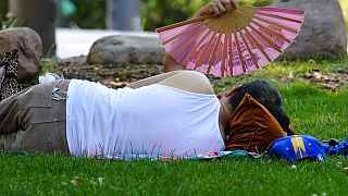 Una mujer utiliza un abanico para refrescarse en un parque de Madrid, España, el martes 12 de julio de 2022.