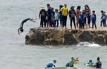 Egy fiatal szörfős ugrik a vízbe Lisszabon Carcavelos strandjánál