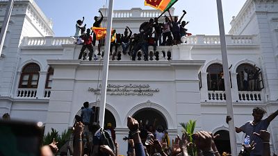 Demonstrators shout slogans and wave Sri Lankan flags during an anti-government protest inside the office building of Sri Lanka's prime minister in Colombo.