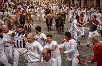 La gente corre por las calles con toros y novillos de lidia durante el último día de los encierros de las fiestas de San Fermín en Pamplona, el jueves 14 de julio de 2022