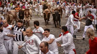 La gente corre por las calles con toros y novillos de lidia durante el último día de los encierros de las fiestas de San Fermín en Pamplona, el jueves 14 de julio de 2022