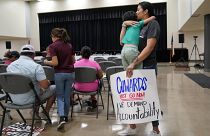 Манифестантка с плакатом на заседании городского совета Увальда (Техас), 12 июля 2022 г.