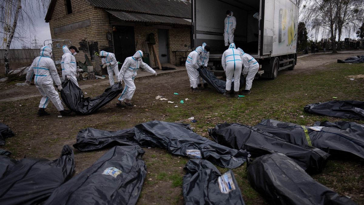 Volunteers load bodies of civilians killed in Bucha onto a truck to be taken to a morgue for investigation, in the outskirts of Kyiv, Ukraine, Tuesday, April 12, 2022. 
