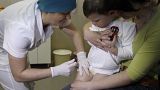 A nurse administers a combined vaccine against diphtheria, whooping cough and tetanus vaccine to a 2-year-old while his mother Inna holds him in Kyiv, Ukraine, April 2013. 