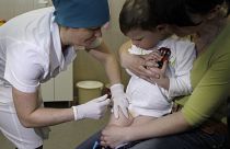 A nurse administers a combined vaccine against diphtheria, whooping cough and tetanus vaccine to a 2-year-old while his mother Inna holds him in Kyiv, Ukraine, April 2013.