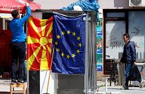 A street vendor fixes a North Macedonia flag next to an EU flag in a street in Skopje, North Macedonia, May 3, 2019. 
