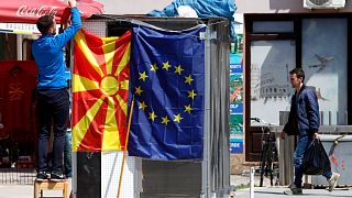 A street vendor fixes a North Macedonia flag next to an EU flag in a street in Skopje, North Macedonia, May 3, 2019.