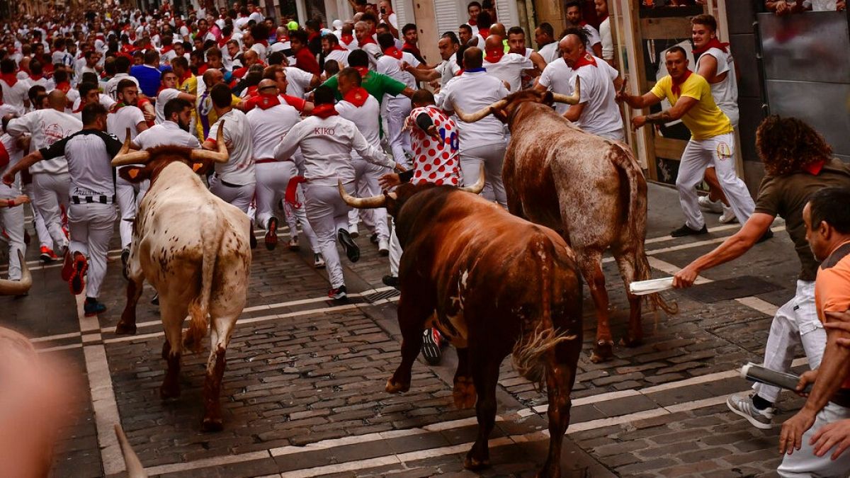 People run through the streets with fighting bulls during the last day of the running of the bulls at the San Fermin festival in Pamplona, Spain, Thursday, July 14, 2022