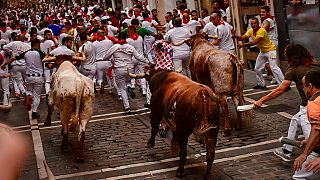 People run through the streets with fighting bulls during the last day of the running of the bulls at the San Fermin festival in Pamplona, Spain, Thursday, July 14, 2022