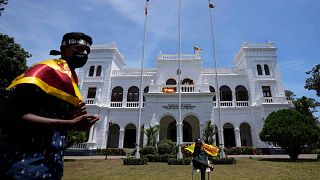 Protesters holding national flags prepare to vacate prime minister Ranil Wickremesinghe's office building with other protesters in Colombo, Sri Lanka, Thursday, July 14, 2022.
