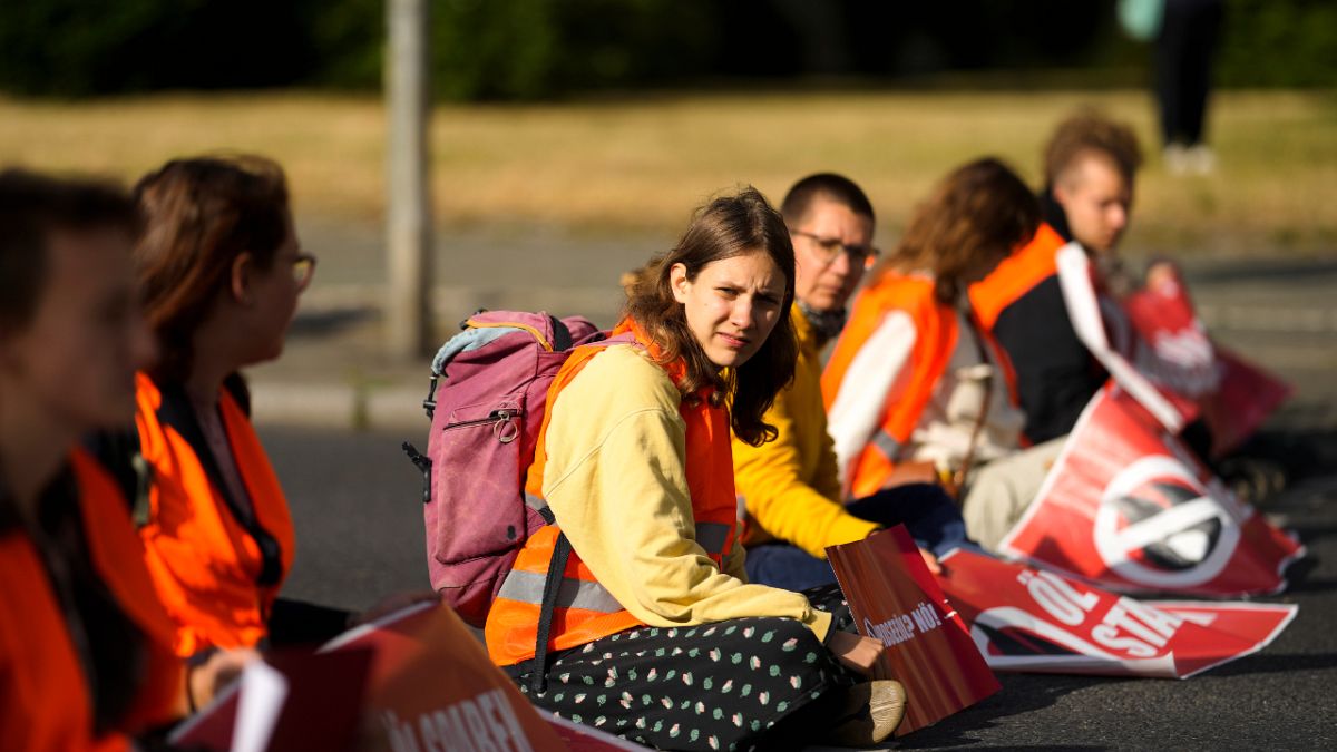 الألمانية لينا شينغوته تجلس مع زملائها في مجموعة "انتفاضة الجيل الأخير" وقد ألصقوا أيديهم في الشارع احتجاجاً على فشل الحكومة في ملف أزمة التغير المناخي. برلين، 21 يونيو 2022.