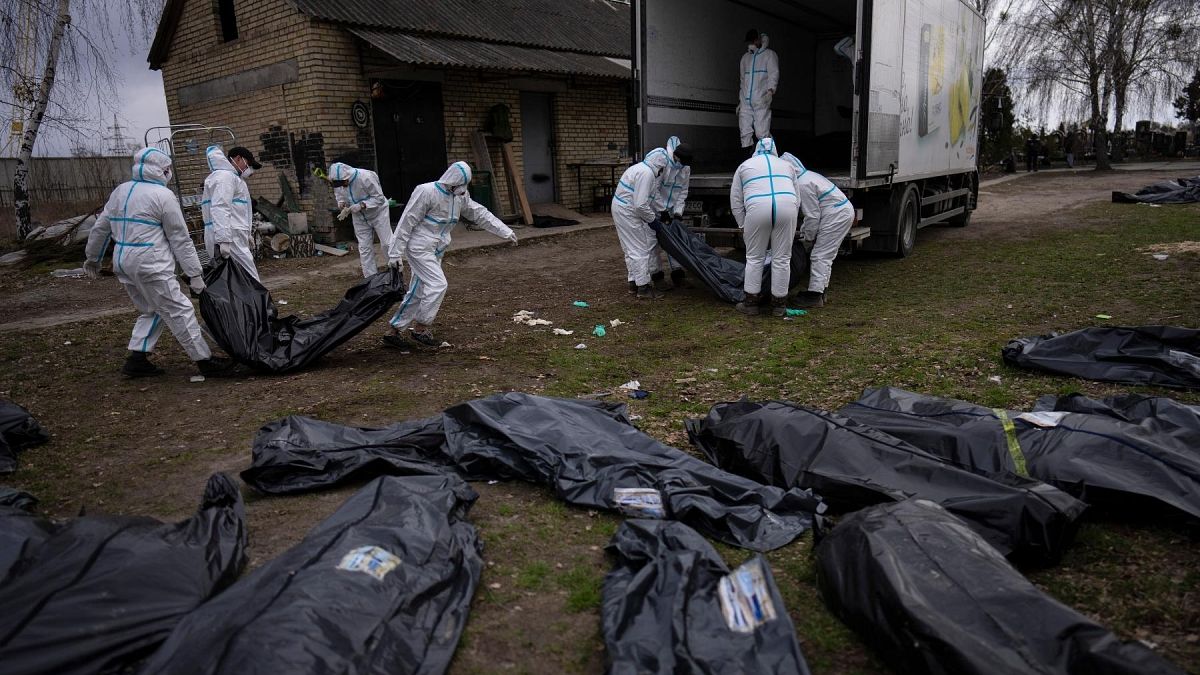 FILE - Volunteers load bodies of civilians killed in Bucha onto a truck to be taken to a morgue for investigation, in the outskirts of Kyiv, Ukraine, Tuesday, April 12, 2022.
