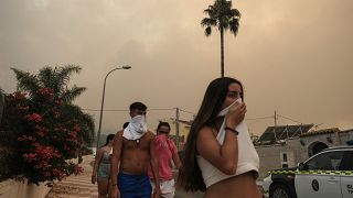 Los residentes se protegen del humo mientras un incendio forestal avanza cerca de una zona residencial en Alhaurín de la Torre, Málaga, España, el 16 de julio de 2022.